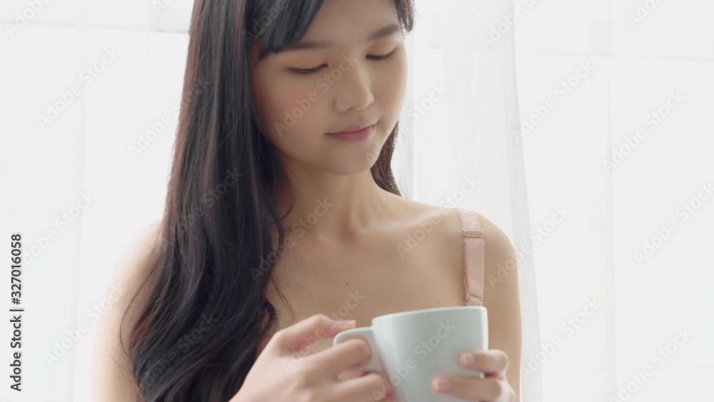 Beautiful young asian woman happy and confident drinking cup of coffee with fresh and looking windows at home, lifestyle asia girl relax in the room at home for wellness and health concept. Beautiful young asian woman happy and confident drinking cup of coffee with fresh and looking windows at home, lifestyle asia girl relax in the room at home for wellness and health concept.