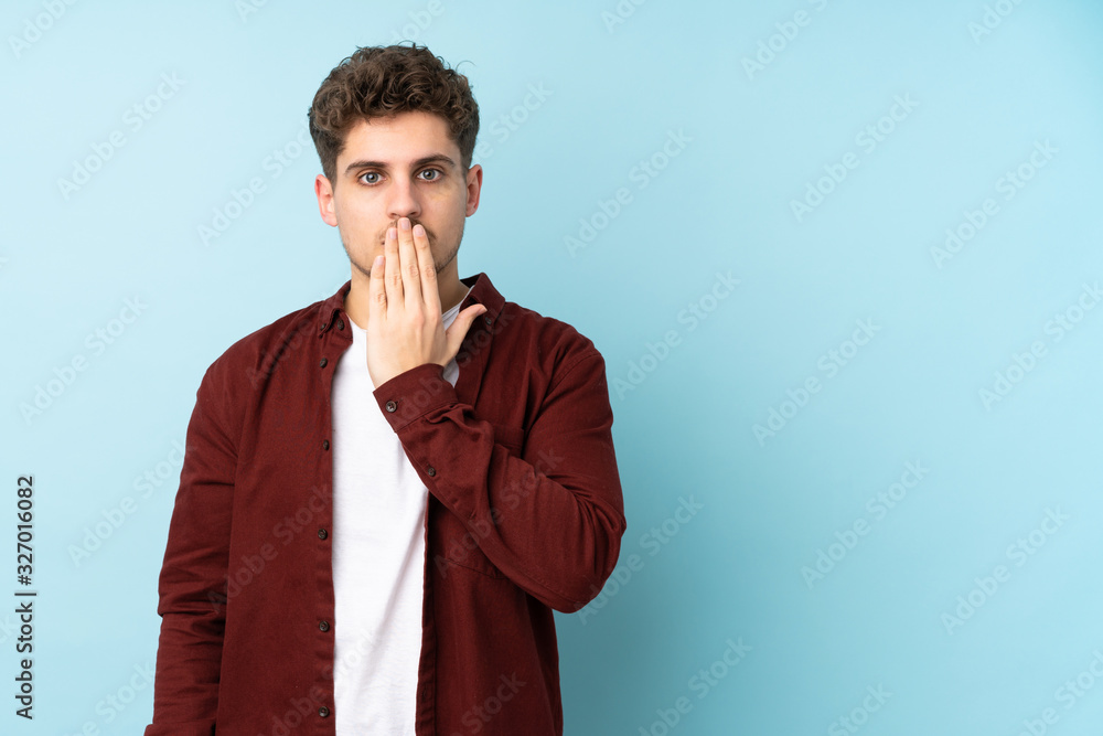 Young caucasian man isolated background covering mouth with hand Young caucasian man isolated background covering mouth with hand
