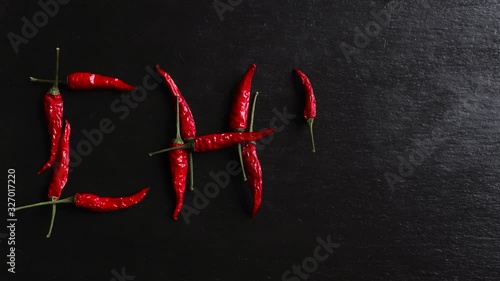 Stop motion animation of red hot peppers writing chili on slate background