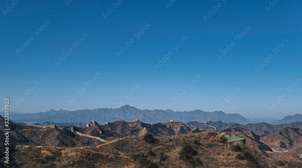 Wide shot of Great Wall of China on slightly snowy day with blue sky