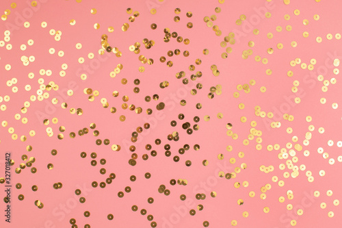 Pink pastel festive background with golden sparkling sequins. Abstract backdrop with confetti.