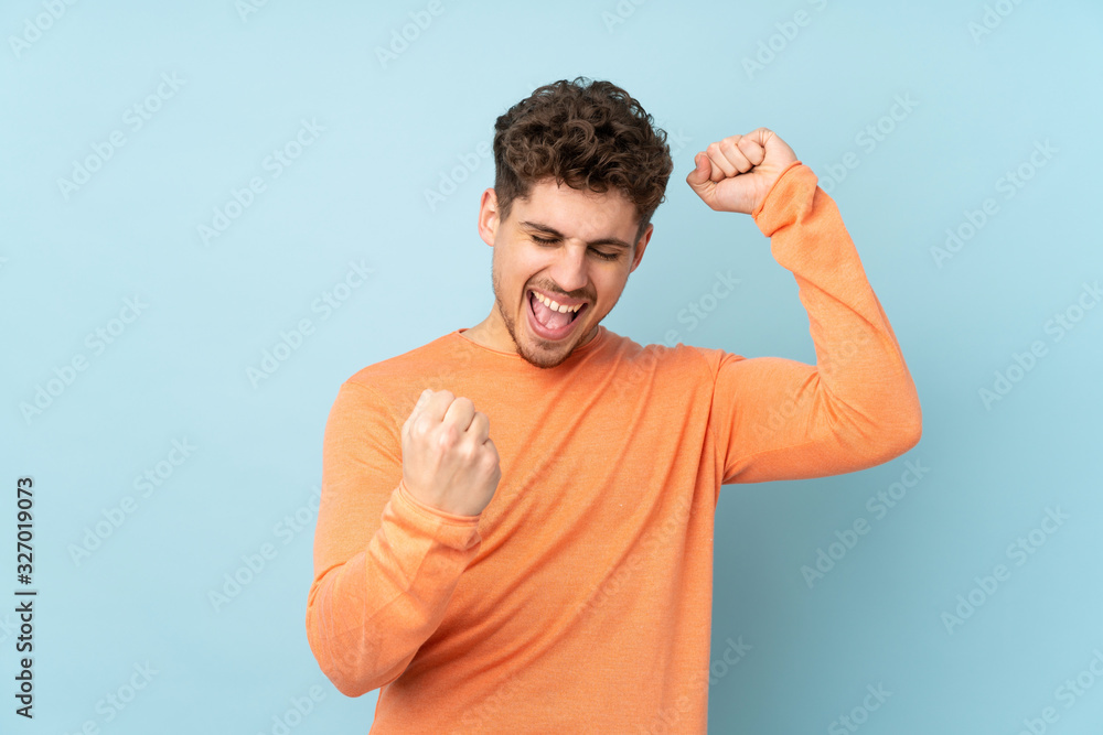Naklejka premium Caucasian man isolated on blue background celebrating a victory