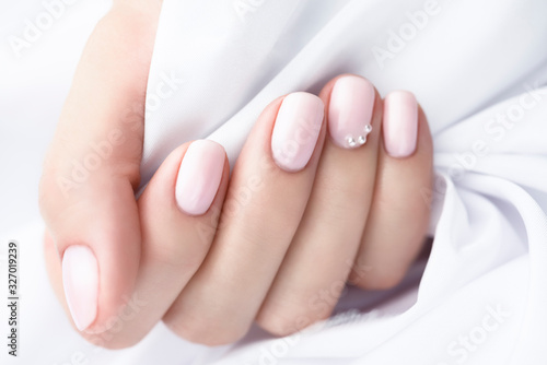 Nude Nail Polish. Beige manicure with pearls on a white background. 