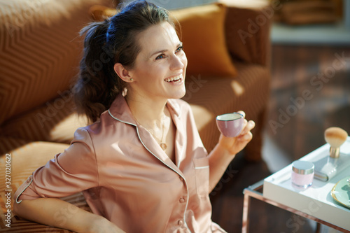 happy modern woman drinking coffee near table with toiletries