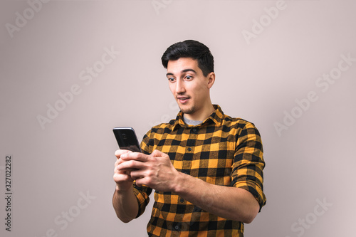 young man looking into his phone amazed by unbelievable news or social media post