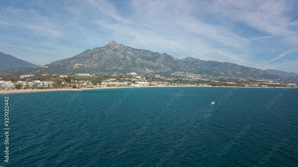 a boat navigating in from of marbella coast, malaga in the south of Spain, views of all shore in the picture of marbella town