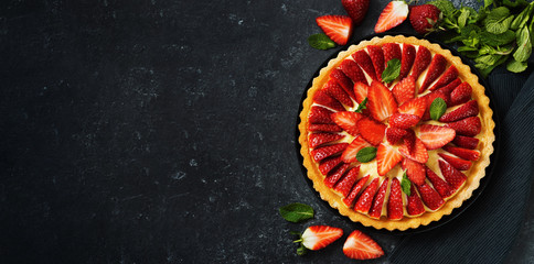 Top view of fresh strawberry flan cake on black background