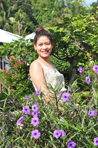 Beautiful girl with purple flowers at the resort and the beach view of the beautiful beach of Koh Samet.