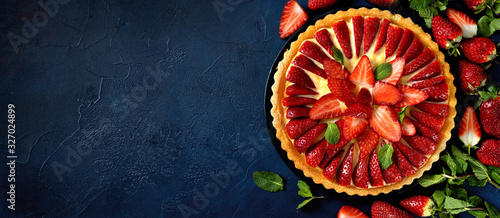Delicious fresh strawberry tart on trendy dark blue background