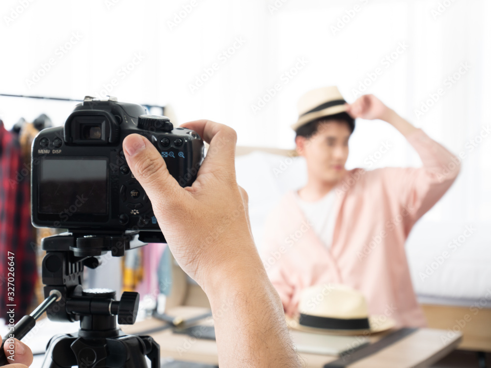 Asian camera man shooting and touch record live button for review and promote hat accessory fashion e-commerce business before share on social media for sell or create post content in studio room