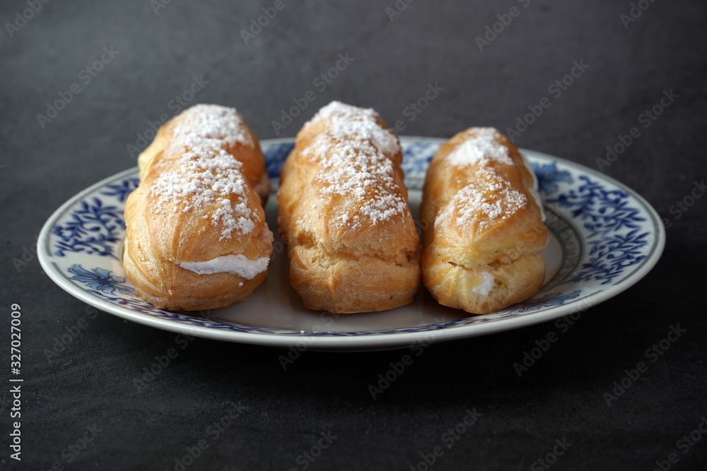 Eclairs with cream and powdered sugar on a plate