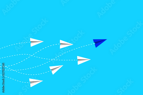 Leadership and competition concept, with blue paper plane leading among white on blue sky.