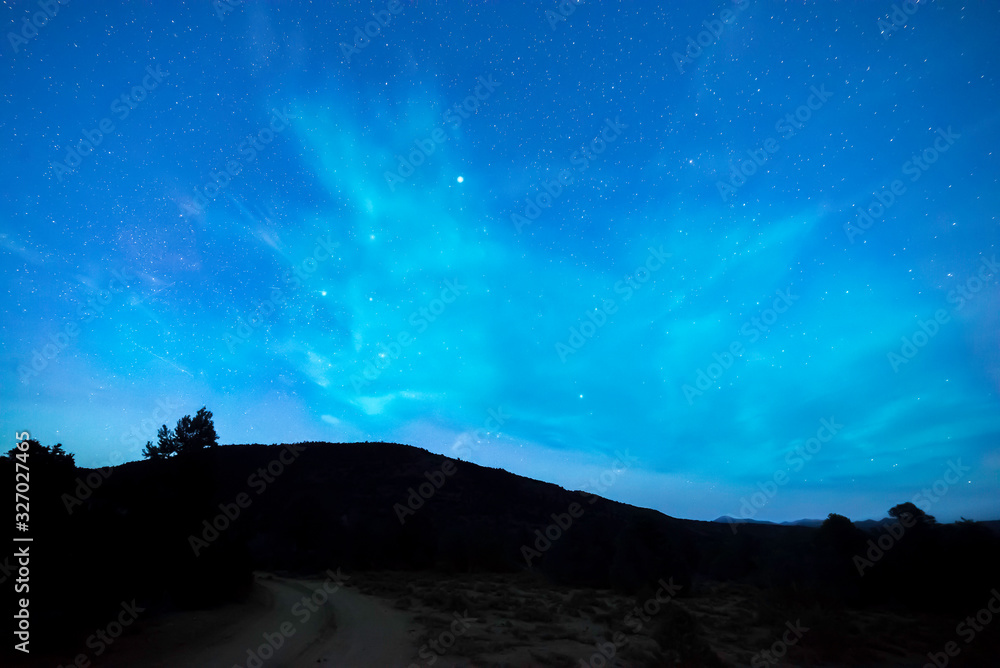 Surreal Night Sky with Aqua Cloud against starry blue background with silhouette of the mountains of the Monitor Range in Nye County, Nevada, USA.