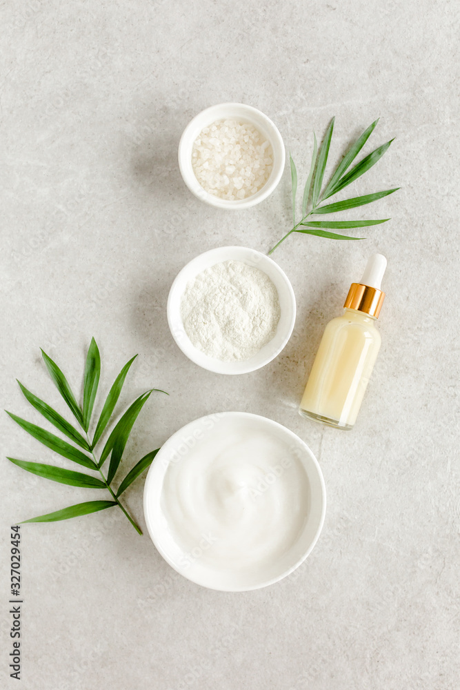 Female skin and body care cosmetic products set: facial cream, cosmetic clay, sea salt, bottle with hyaluronic on gray marble background. Beauty blogger, salon treatments concept. Flat lay, top view Female skin and body care cosmetic products set: facial cream, cosmetic clay, sea salt, bottle with hyaluronic on gray marble background. Beauty blogger, salon treatments concept. Flat lay, top view