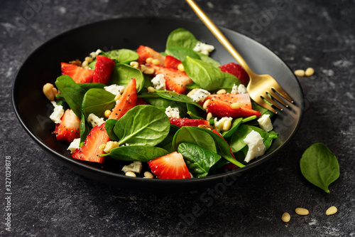 Close up of healthy strawberry salad with spinach, feta and pine nuts