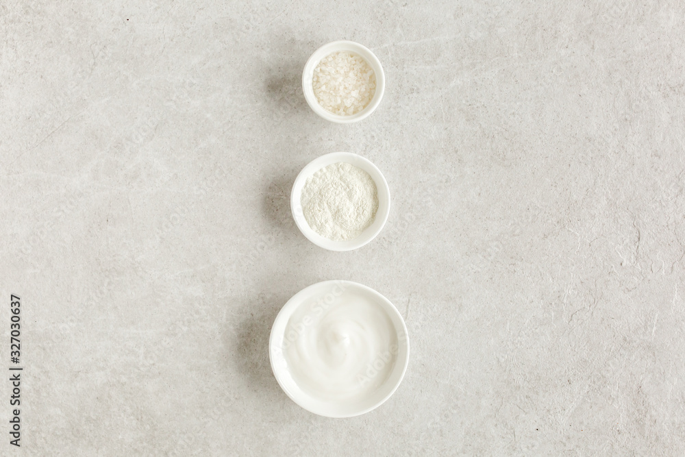 Three various natural spa cosmetics products in a bowl: facial cream, cosmetic clay, sea salt on gray marble background. Skincare concept. Beauty blogger, salon treatments concept. Flat lay, top view Three various natural spa cosmetics products in a bowl: facial cream, cosmetic clay, sea salt on gray marble background. Skincare concept. Beauty blogger, salon treatments concept. Flat lay, top view