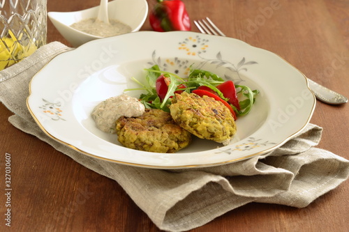 Lentil fritters with zucchini. Served with fresh vegetables and sauce.