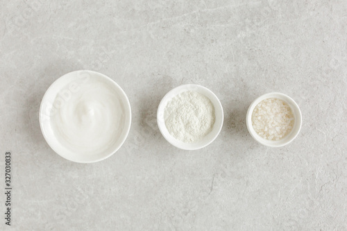 Three various natural spa cosmetics products in a bowl: facial cream, cosmetic clay, sea salt on gray marble background. Skincare concept. Beauty blogger, salon treatments concept. Flat lay, top view