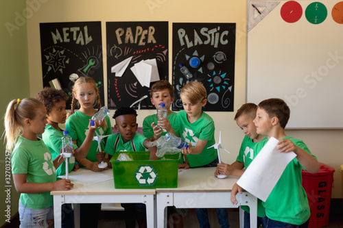 Group of schoolchildren wearing green t shirts with a white recycling logo on them standing around a photo