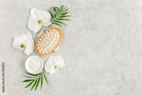 Spa treatment concept. Natural/Organic spa cosmetics products, sea salt, massage brush, tropic palm leaves on gray marble table from above. Spa background with a space for a text, flat lay, top view