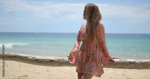 Stylish ethnic woman leaning on fence on beach