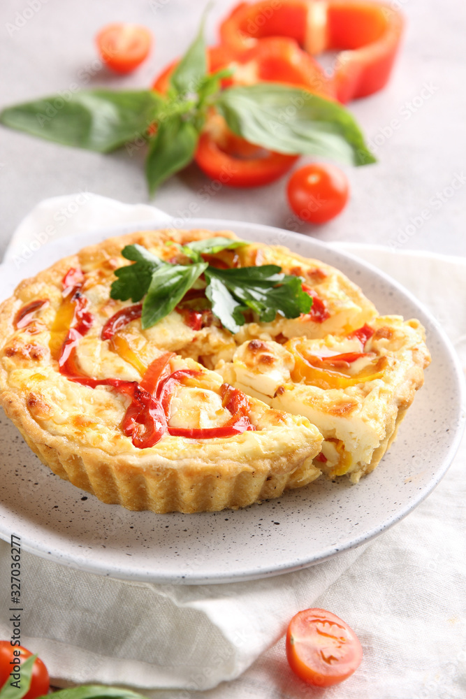 The concept of French cuisine. .Quiche with peppers, tomatoes and cheese on a light background. Background image, copy space The concept of French cuisine. .Quiche with peppers, tomatoes and cheese on a light background. Background image, copy space