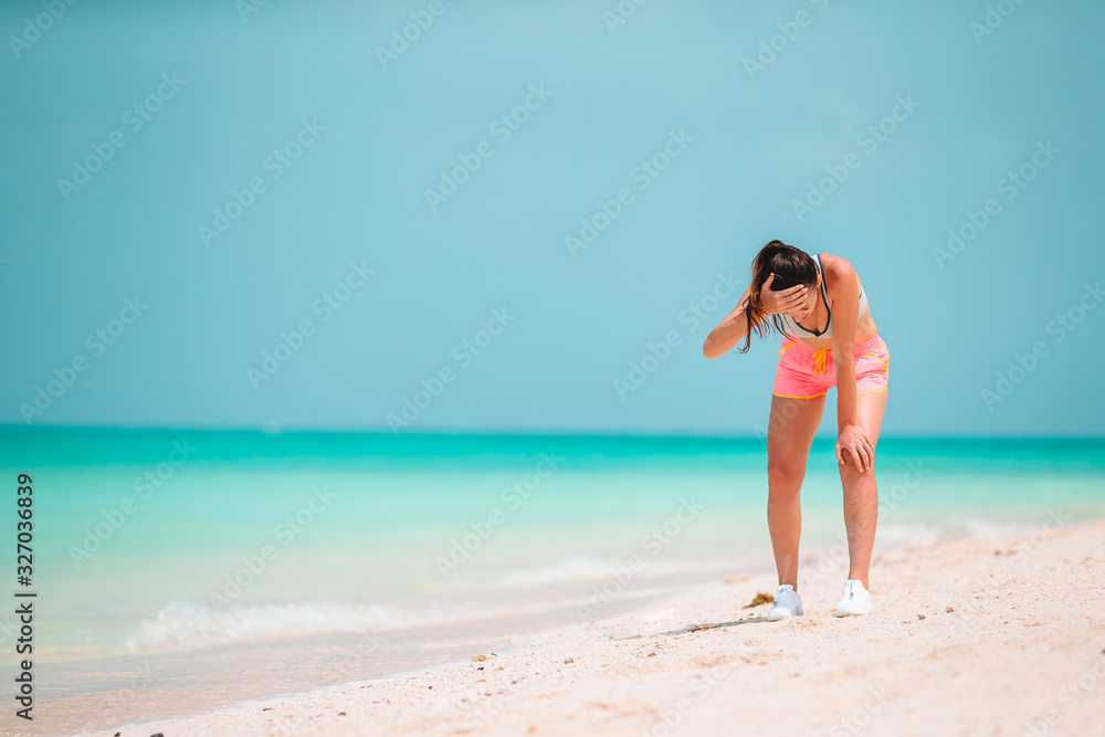 Fit young woman doing exercises on tropical white beach in her sportswear Fit young woman doing exercises on tropical white beach in her sportswear