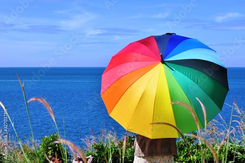 Beautiful women with colorful umbrellas on a hill overlooking the seaside of Koh Samet.