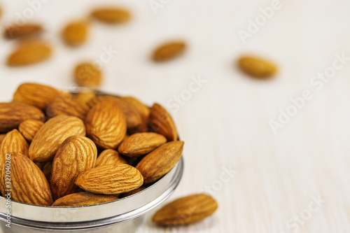 Almonds in a metal bowl and on a white surface