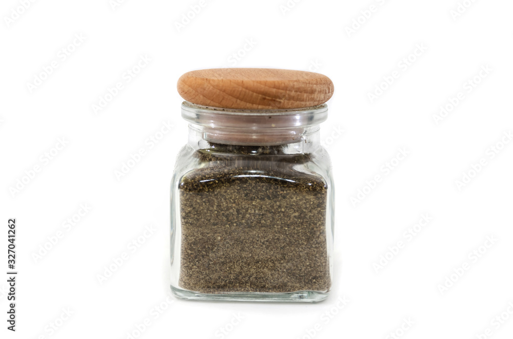 black, ground pepper in a container for spices isolated on a white background.