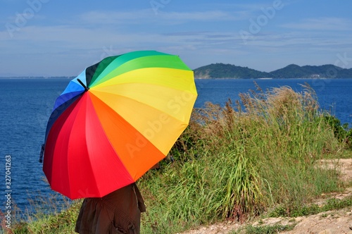 Beautiful women with colorful umbrellas on a hill overlooking the seaside of Koh Samet.