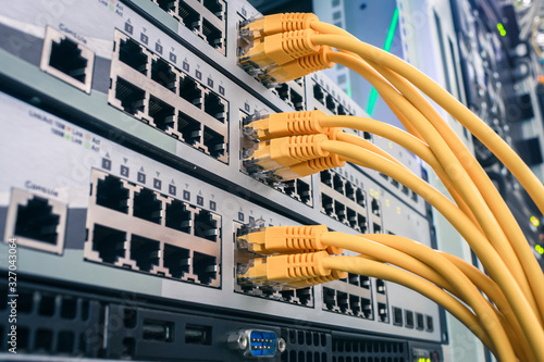 A bunch of yellow communication cables connect to the router interfaces. Telecommunication equipment is in the server room of the data center. Technology concept