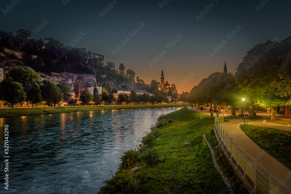 sky line and city lights of Saluzburg city over the salzach river at sunset