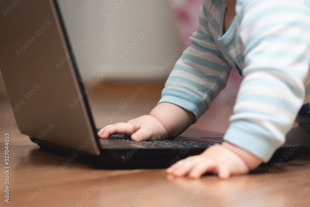 Fototapeta premium Baby is studying a laptop on the floor close up.