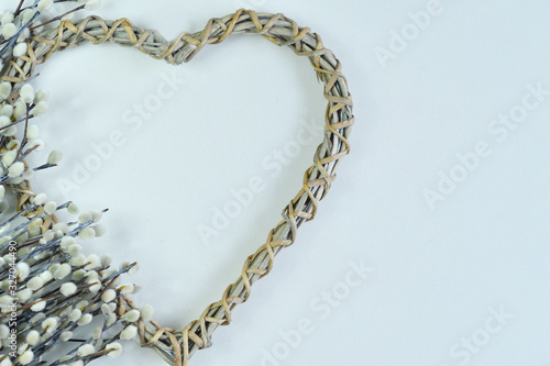 fluffy willow twigs and wicker heart on a white background