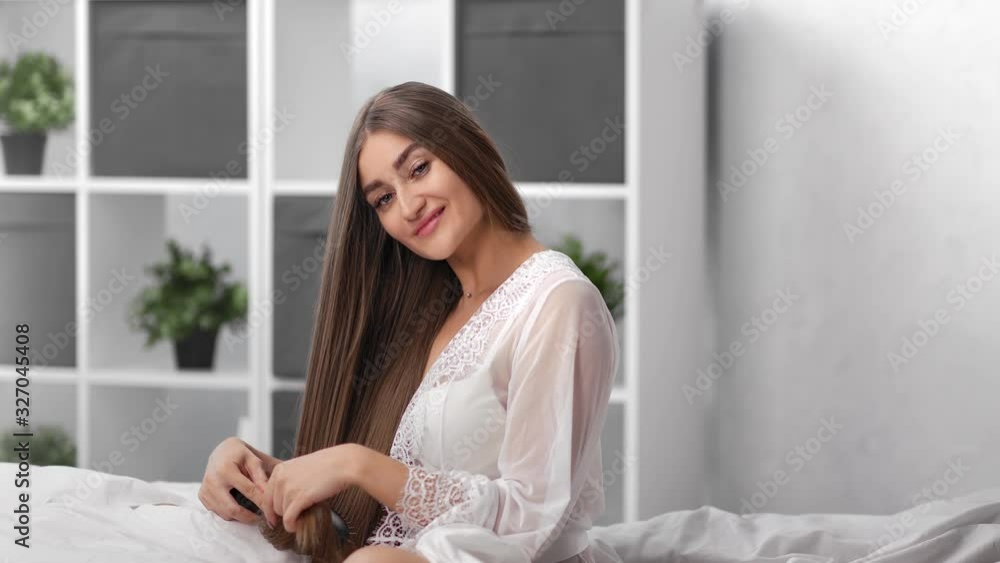 Adorable smiling girl in sexy dressing gown comb long beautiful hair. Medium shot on RED camera Adorable smiling girl in sexy dressing gown comb long beautiful hair. Medium shot on RED camera