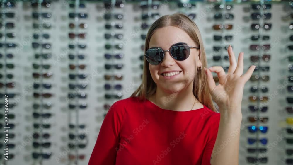 Young woman with eyeglasses. Woman in sunglasses standing in optic store Young woman with eyeglasses. Woman in sunglasses standing in optic store