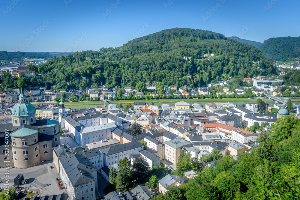 Aerial view of Salzburg Cathedral and the surrounding houses with a green hill in the back ground