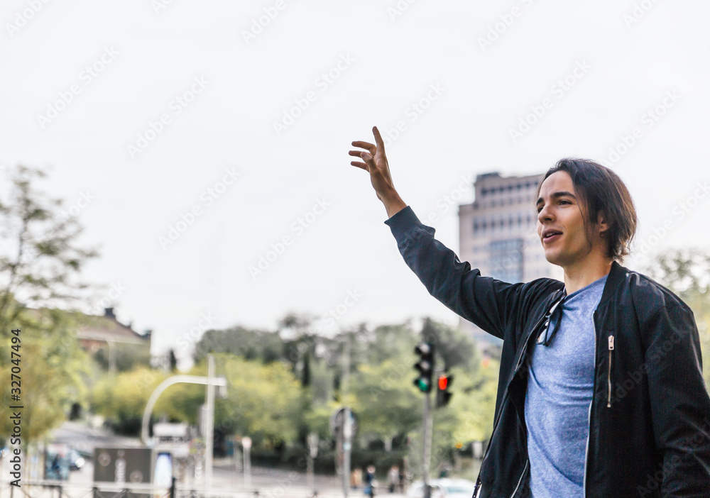 Attractive young black haired caucasian man stops a taxi or bus in the middle of a street Attractive young black haired caucasian man stops a taxi or bus in the middle of a street
