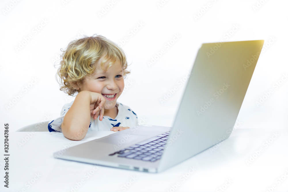 A young child with cheerful expression between 4 and 5 years old sitting at a desk while using a computer A young child with cheerful expression between 4 and 5 years old sitting at a desk while using a computer
