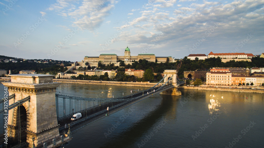 Fototapeta premium Drone view of Szechenyi Chain Bridge, Clark Adam Square. Buda Castle Royal Palace and Buda Tunnel at sunrise on a summer morning. Buda castle in the background.