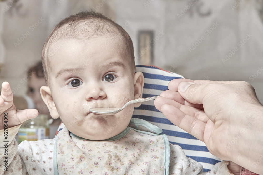 cute adorable baby eating porridge with a spoonful of the concept of proper nutrition cute adorable baby eating porridge with a spoonful of the concept of proper nutrition