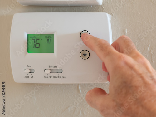 Setting digital thermostat to cool and programming air conditioning to energy saving temperature of 78 degrees.