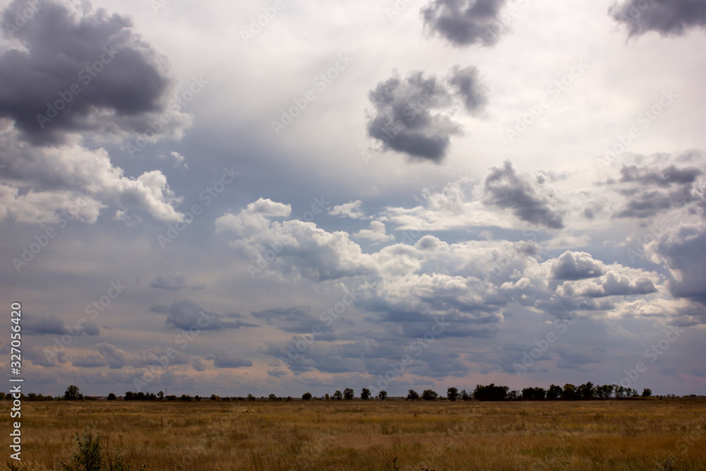 huge cumulus rain clouds and clouds in the sky in the sunshine above the field