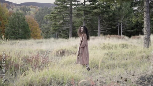 Beautiful girl walking in the forest, turning and looking at the camera