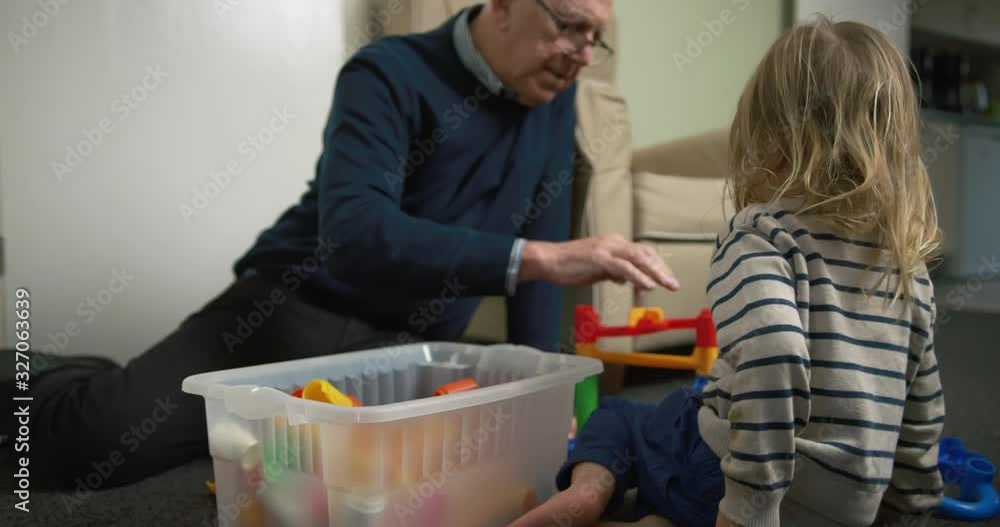 Preschooler and his grandfather playing with marble run Preschooler and his grandfather playing with marble run
