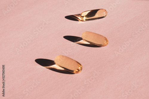 Liquid gelatin capsules with flower shadow on pink background
