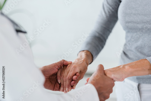 Fototapeta Hands of a doctor holding hands of elderly patient
