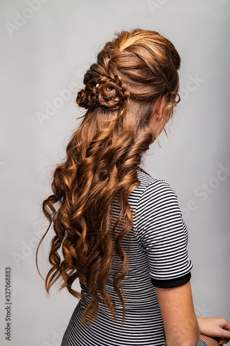 Wave curls hairstyle. Hairstyle on red brown hair woman with long hair on gray background. Professional hairdressing services.Hair styling, making braid with hairpin.