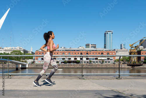 Latin American woman with a pink outfit jogging in Puerto Madero, Buenos Aires